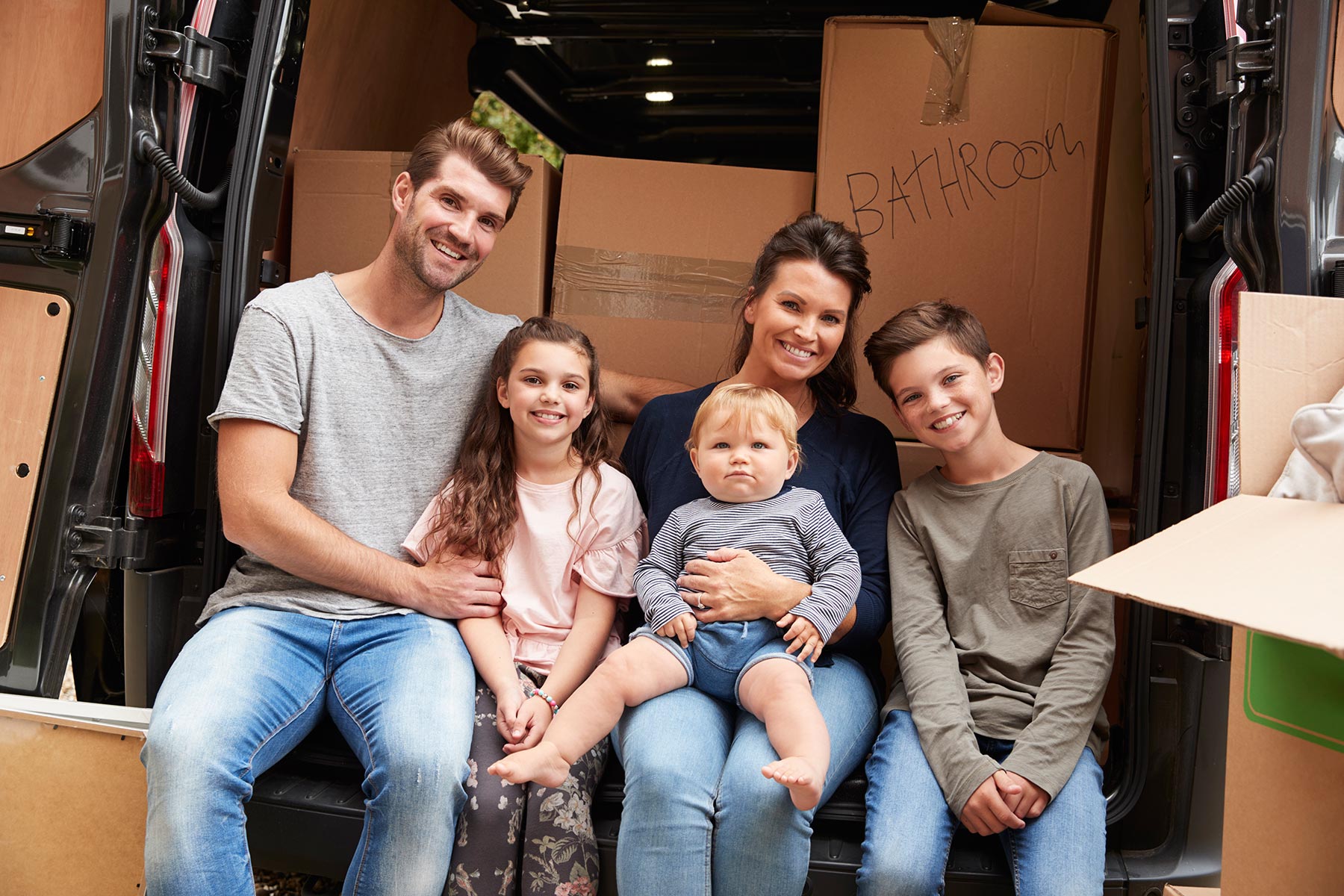 Military family sitting in back of moving truck - PCS relocation and household goods transport